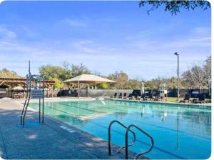 ein Pool mit blauem Wasser und einem Sonnenschirm in der Unterkunft Cozy Sunterro Serenity in North Austin Pet Friendly in Austin