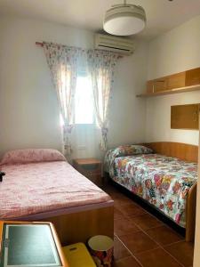 a small room with two beds and a window at Chalet Familiar Relax con piscina in Chiclana de la Frontera