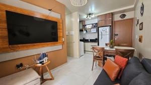 a living room with a couch and a flat screen tv at PERFEITO 1dorm, piscina, Intermares com garagem in Nossa Senhora do Livramento