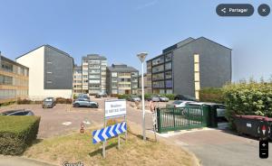 a parking lot with some buildings and a sign at Appartement vue sur mer & le port de Courseulles-sur-Mer in Courseulles-sur-Mer