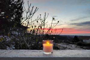 a candle sitting on a ledge with a sunset in the background at Refúgio da Alma in Mafra