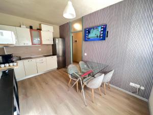 een keuken met een glazen tafel met stoelen en een koelkast bij Egles Apartments Lignano Sabbiadoro Arena Beach in Lignano Sabbiadoro