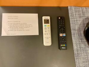 two remote controls and a card on a table at Estudio no Centro de Curitiba in Curitiba
