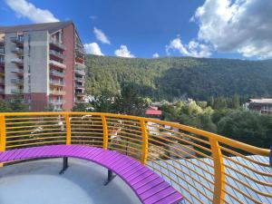 a balcony with a purple and yellow railing with a mountain at Sinaia Mountain View Residence Belleview in Sinaia