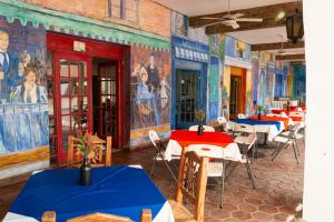 a room with tables and chairs and paintings on the walls at Hotel Hacienda Bugambilias La Paz in La Paz