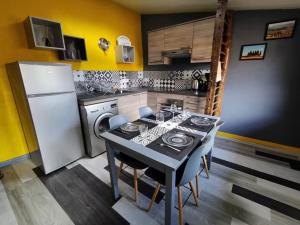 a kitchen with a table and a white refrigerator at Chez Mathilde et Kévin in Saint-Maurice