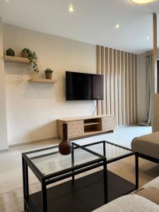 Una sala de estar con televisión y una mesa de centro de cristal. en L&K Apartment, en Metzingen