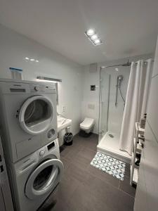 a bathroom with a washing machine and a shower at Al Nafurah Apartments in Munich