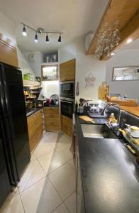 een keuken met een spoelbak en een zwarte koelkast bij Studio cocooning - Terrasse - Jardin - Piscine in Menton