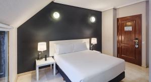a bedroom with a white bed and a black wall at Sercotel Togumar in Madrid +34 photos