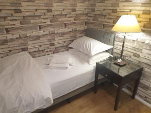 ein Schlafzimmer mit einem Bett und einem Tisch mit einer Lampe in der Unterkunft Spacious, Stylish Two-Bedroom Maisonette, Modern Amenities, Elegant Interiors in Buckinghamshire