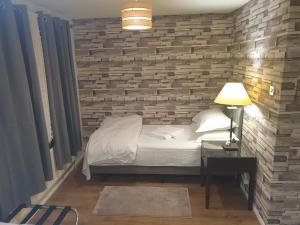 ein Schlafzimmer mit einer Ziegelwand mit einem Bett und einer Lampe in der Unterkunft Spacious, Stylish Two-Bedroom Maisonette, Modern Amenities, Elegant Interiors in Buckinghamshire