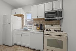 una cucina con armadietti bianchi, piano cottura e forno a microonde di Spacious 3-Bedroom Apartment near NYC - 15min to Times Square, Empire State Building, Central Park, Statue of Liberty a Jersey City