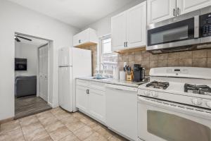 una cucina con armadi bianchi e un piano cottura bianco con forno di Spacious 3-Bedroom Apartment near NYC - 15min to Times Square, Empire State Building, Central Park, Statue of Liberty a Jersey City Altre 15 foto