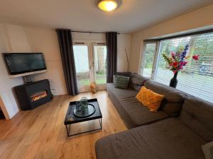 a living room with a couch and a fireplace at Heerlijk chalet midden in de natuur in Putten
