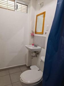 ein Badezimmer mit einer weißen Toilette und einem Waschbecken in der Unterkunft Departamento En Acapulco Diamante con Alberca, Camastros y Hermosos Jardines in Acapulco