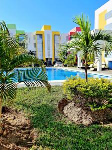 ein Swimmingpool mit Palmen vor einem Gebäude in der Unterkunft Departamento En Acapulco Diamante con Alberca, Camastros y Hermosos Jardines in Acapulco + 4 Fotos