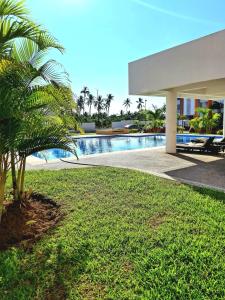 eine Palme vor einem Haus mit Pool in der Unterkunft Departamento En Acapulco Diamante con Alberca, Camastros y Hermosos Jardines in Acapulco