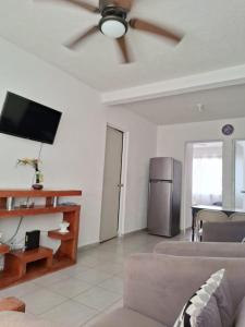 ein Wohnzimmer mit einer Couch und einem Deckenventilator in der Unterkunft Departamento En Acapulco Diamante con Alberca, Camastros y Hermosos Jardines in Acapulco