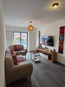 a living room with a couch and a tv at Acogedor Departamento en Cusco, Ideal para Familias y Amigos, Equipado y Céntrico in Cusco