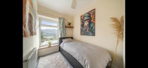 ein kleines Schlafzimmer mit einem Bett und einem Fenster in der Unterkunft Quirky Mountain Cottage in Pontardawe