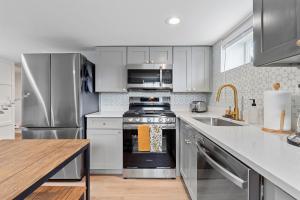 eine Küche mit einem Edelstahlherd und einer Spüle in der Unterkunft Urban Hideaway - Charming 2 Bedroom Apartment Close to Denver's Best Attractions in Denver