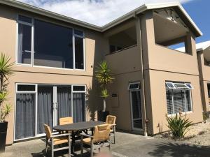 a house with a table and chairs in front of it at Beautiful 3 bedroom apartment, only steps to the golden sand in Kaiteriteri