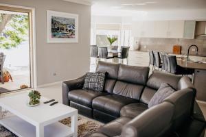 a living room with a leather couch and a table at Riverside Retreat Pool, Pontoon & Space in Gold Coast
