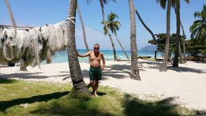 Un uomo in piedi accanto a una palma sulla spiaggia di House Colonial Style a La Hatte