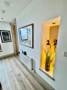 a hallway with a mirror and a plant on a wall at James Clow Boutique Bed & Breakfast in Belfast