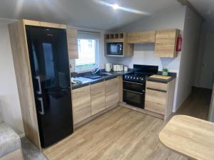 a kitchen with a black refrigerator and wooden cabinets at Marsden Escape in Cayton
