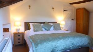 a bedroom with a large bed with two lamps at East Titchberry Cottage - Thatched cottage charm in rural North Devon in Hartland
