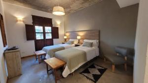 a bedroom with two beds and a table and a chair at Adobe Hotel Fiambalá in Fiambalá
