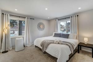 Un dormitorio con una gran cama blanca y ventanas. en Parkside Haven Hot Tub Foosball & Family Fun, en Monument