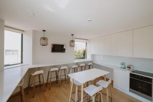 a kitchen with a white counter and bar with stools at 888 Hostel&Suites in São João da Madeira