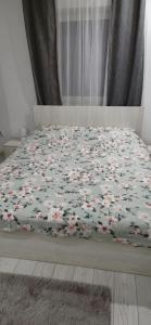 a bed with a blanket with flowers on it at C&C apartamente in Sîngeorgiu de Mureş