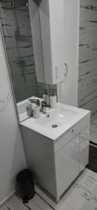 a white bathroom with a sink and a mirror at C&C apartamente in Sîngeorgiu de Mureş