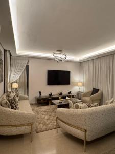 a living room with two couches and a flat screen tv at Zed towers El sheikh ZAYED zed park 3 in Sheikh Zayed