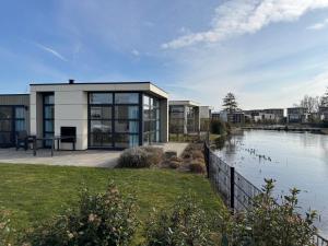 a house with a large window next to a body of water at Marina Strandbad Chalet IJssel Oase mit Zaun Haus Nr 77 in Olburgen
