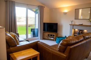 a living room with a couch and a television at Y Caban in Cemaes Bay