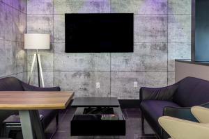 un salon avec un canapé et une télévision sur un mur dans l'établissement Repotel Henri IV Québec, à Québec 19 autres photos