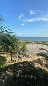 ein Strand mit einem Zaun und Palmen und dem Meer in der Unterkunft Casa Lua Barrinha in Barrinha + 10 Fotos
