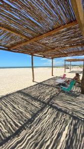 einen Stuhl unter einem Strohschirm am Strand in der Unterkunft Casa Lua Barrinha in Barrinha