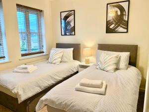 two twin beds in a room with two windows at Spacious & Stylish Stay - Perfect for Families & Contractors ! 3 Bedroom House in Reading upto 3 Free Parking !! in Reading