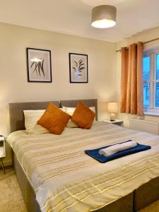 a bedroom with a large bed with orange pillows at Spacious & Stylish Stay - Perfect for Families & Contractors ! 3 Bedroom House in Reading upto 3 Free Parking !! in Reading