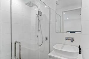 a white bathroom with a shower and a sink at Lakeview Luxury Villa in Wanaka