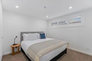 a white bedroom with a bed and two windows at Lakeview Luxury Villa in Wanaka +11 photos