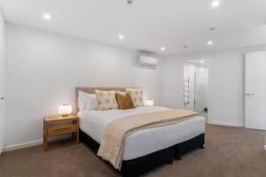 a white bedroom with a bed and a night stand at Lakeview Luxury 2 Bedroom Villa in Wanaka