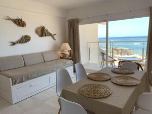 a living room with a couch and a table with chairs at Espardell Beachfront Stay - Ocean Breeze & Sunrise in Es Pujols