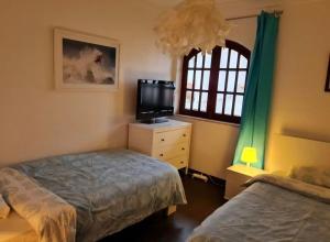 a bedroom with two beds and a tv and a window at Equinoxea in Nazaré